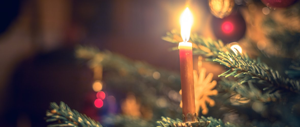 Candle on traditional decorated Christmas tree, evening